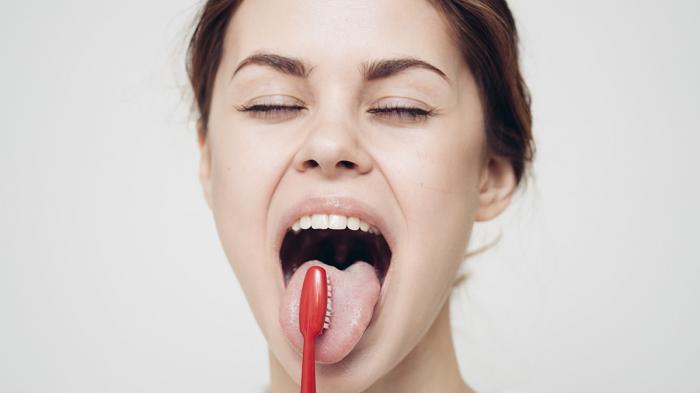 Ilustrasi membersihkan lidah untuk menghilangkan bau mulut saat puasa. (Canva.com)
