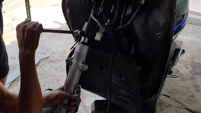 Ilustrasi mekanik yang sedang menservis shockbreaker depan motor. (gridoto.com)